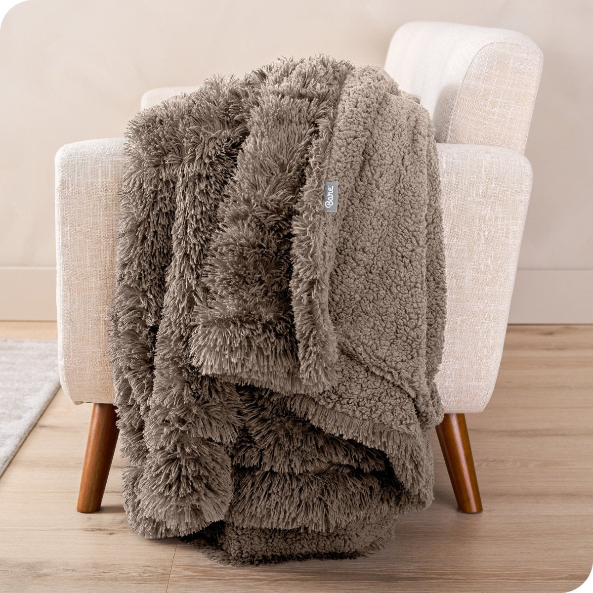 A shaggy faux fur blanket draped over the arm of a chair