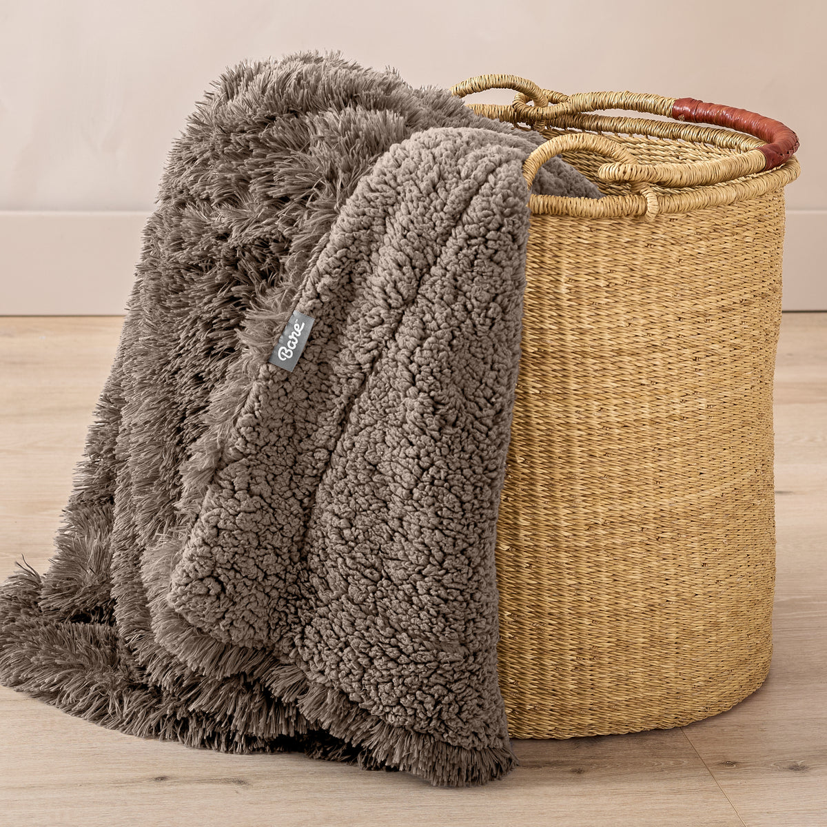 A blanket hanging over the edge of a wicker basket