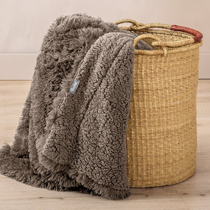 A blanket hanging over the edge of a wicker basket