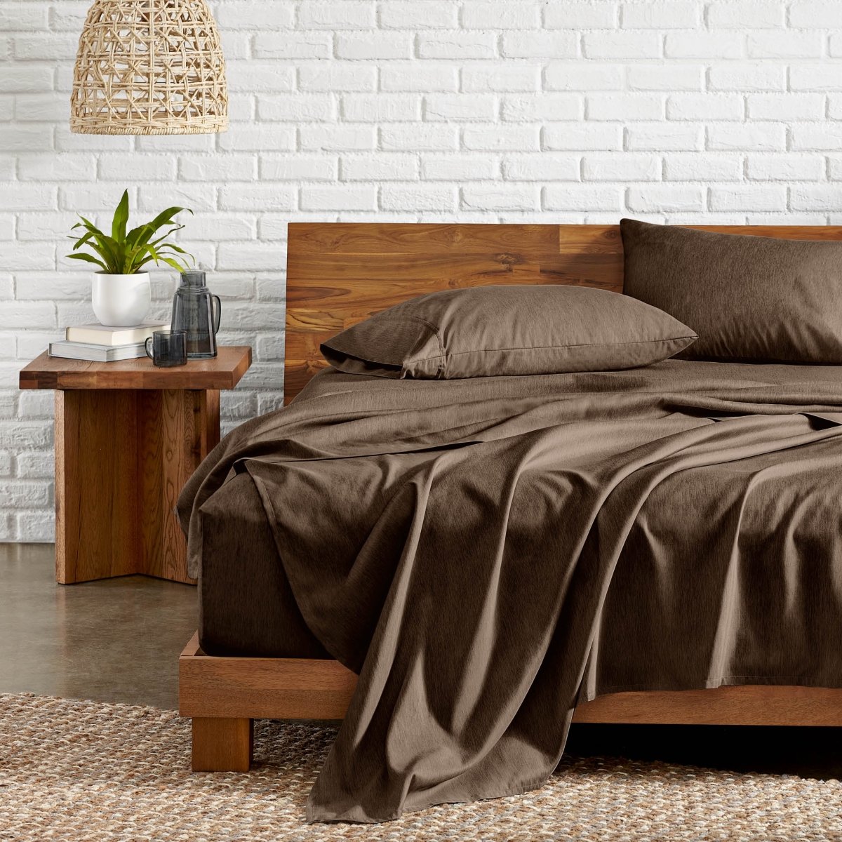 Bedroom with wooden bed, nightstand, and white brick wall.
