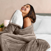 A woman smiling while wrapped in a sherpa blanket