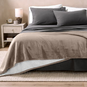 Bed with grey sheets and a sherpa blanket