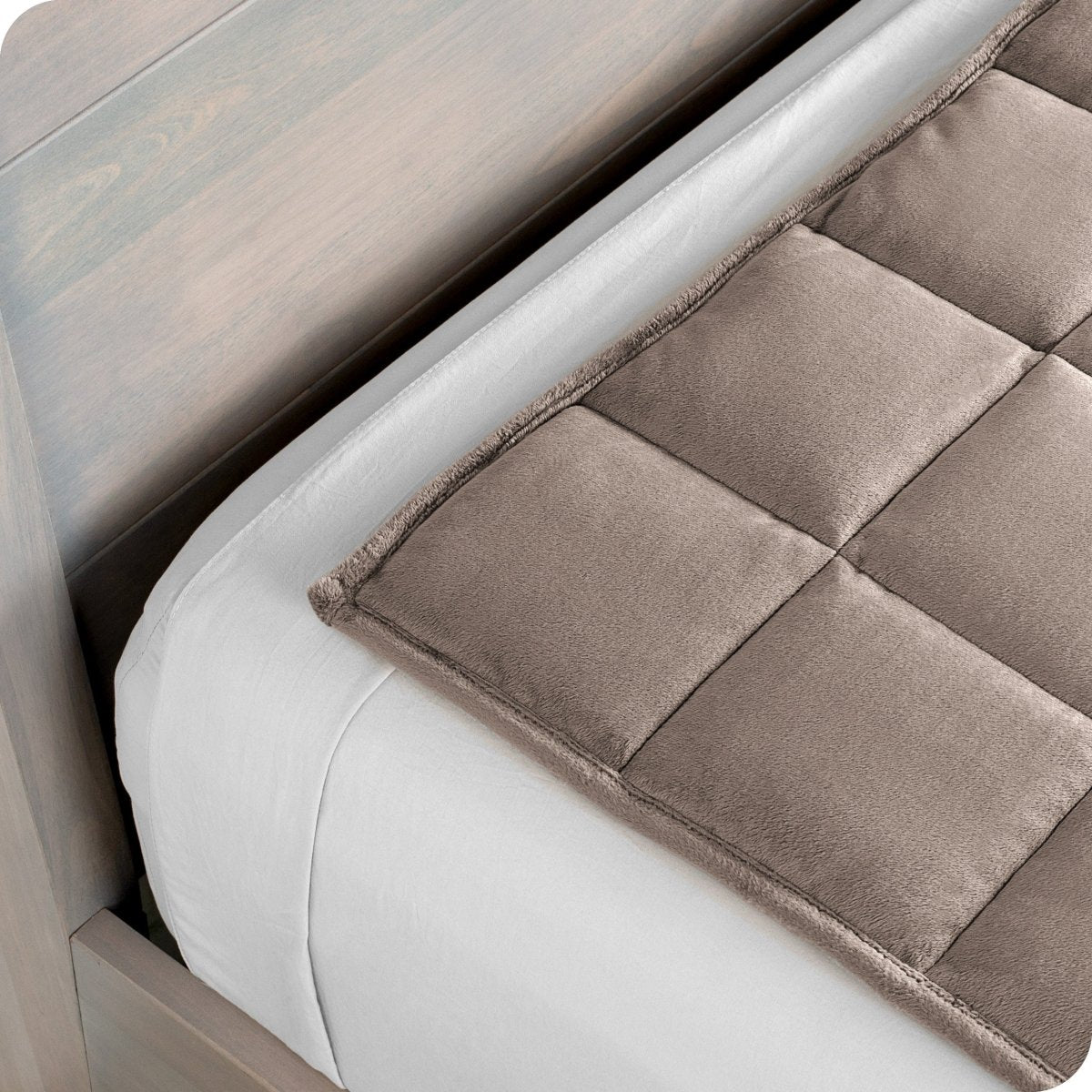 Close up of a weighted blanket on top of a bed made with white sheets