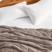 Close up of a weighted blanket on a bed next to pillows
