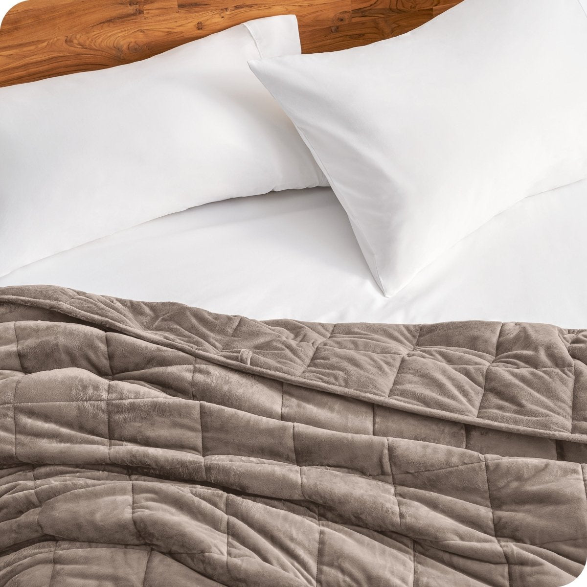 Close up of a weighted blanket on a bed next to pillows