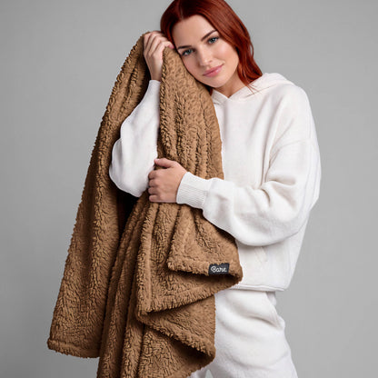 A woman standing while holding a textured blanket