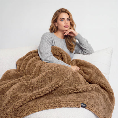A woman sitting on a couch with a blanket over her lap