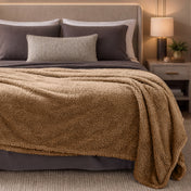 Bed with brown blanket and pillows in a bedroom setting.