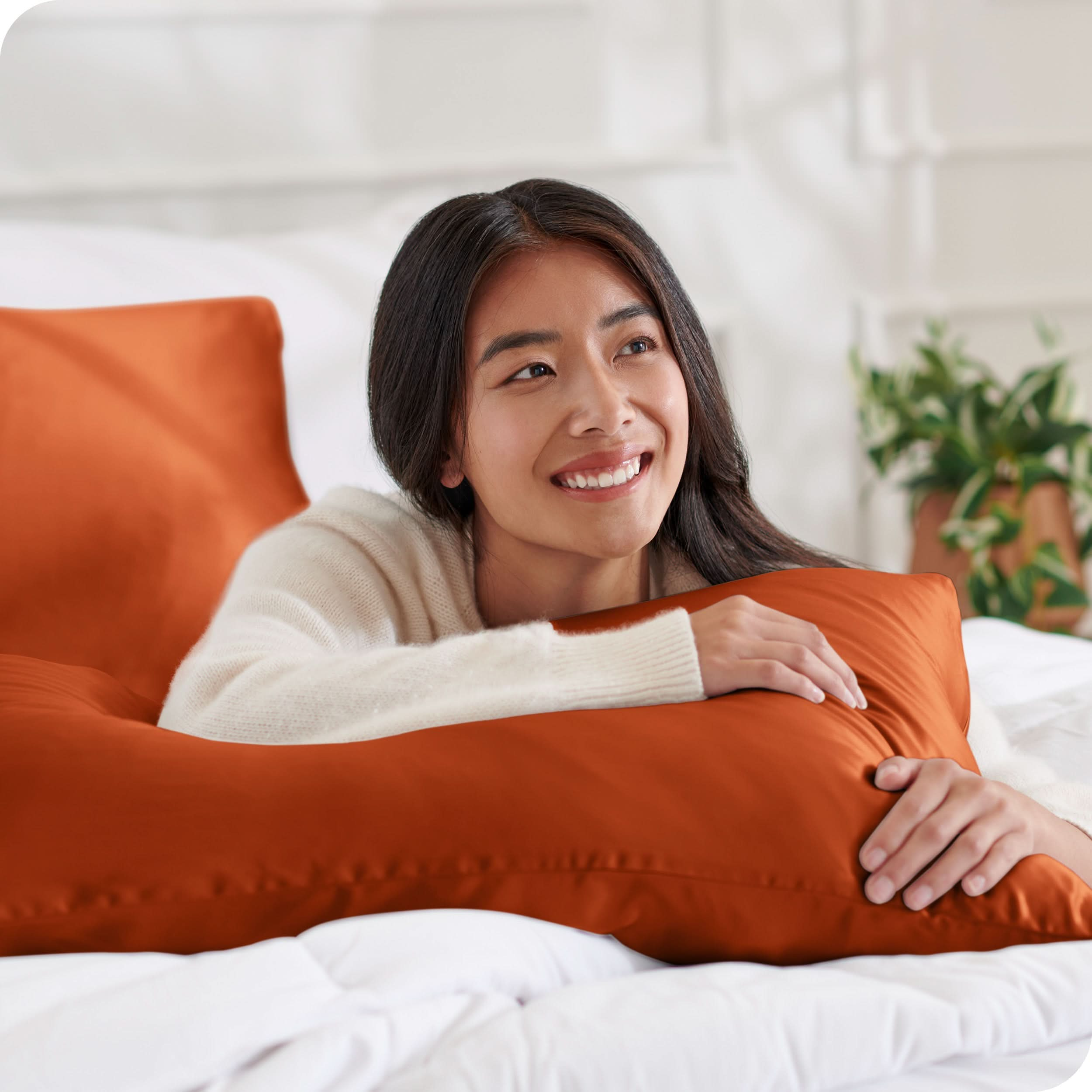 A woman on a bed with a silk pillowcase covered pillow