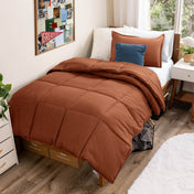Comforter set on a bed in a bedroom with a window and decor.
