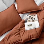 Comforter and pillows on a bed with a magazine and glasses.