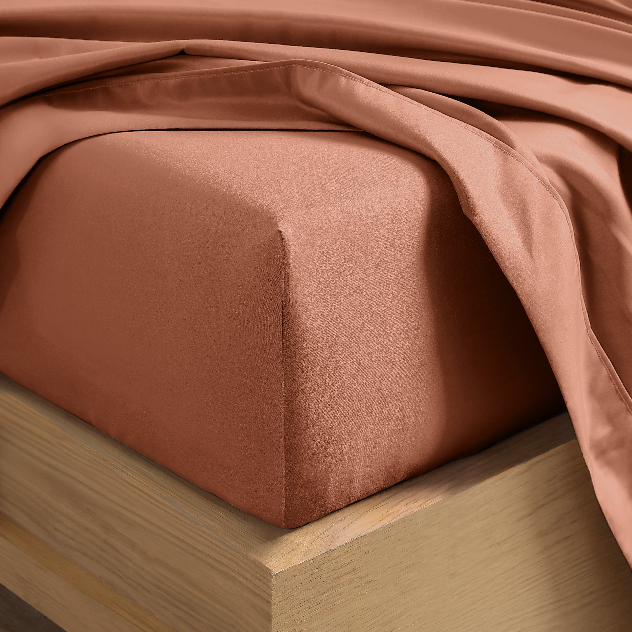 Close up of the corner of a mattress with a fitted sheet and flat sheet on it
