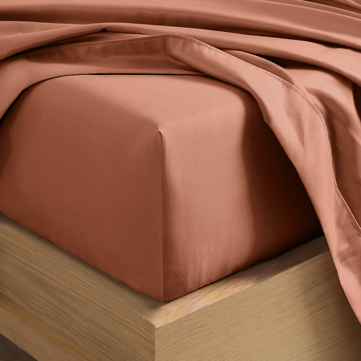 Close up of the corner of a mattress with a fitted sheet and flat sheet on it