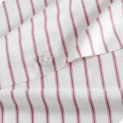 Close-up of a white fabric with thin vertical red pinstripes and a clear plastic button.