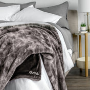 Blanket with 'Bare' branding on a bed in a bedroom setting