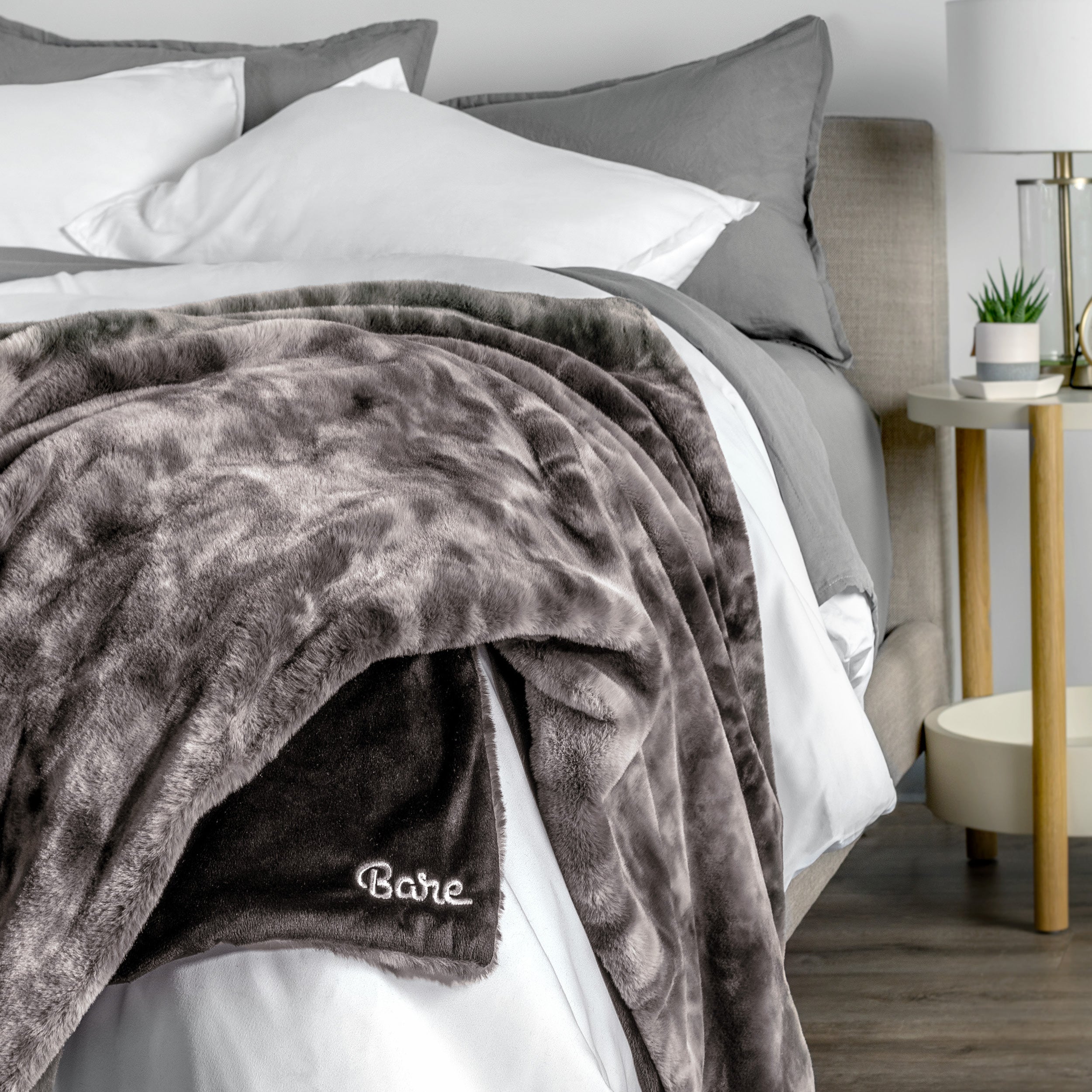 Blanket with 'Bare' branding on a bed in a bedroom setting