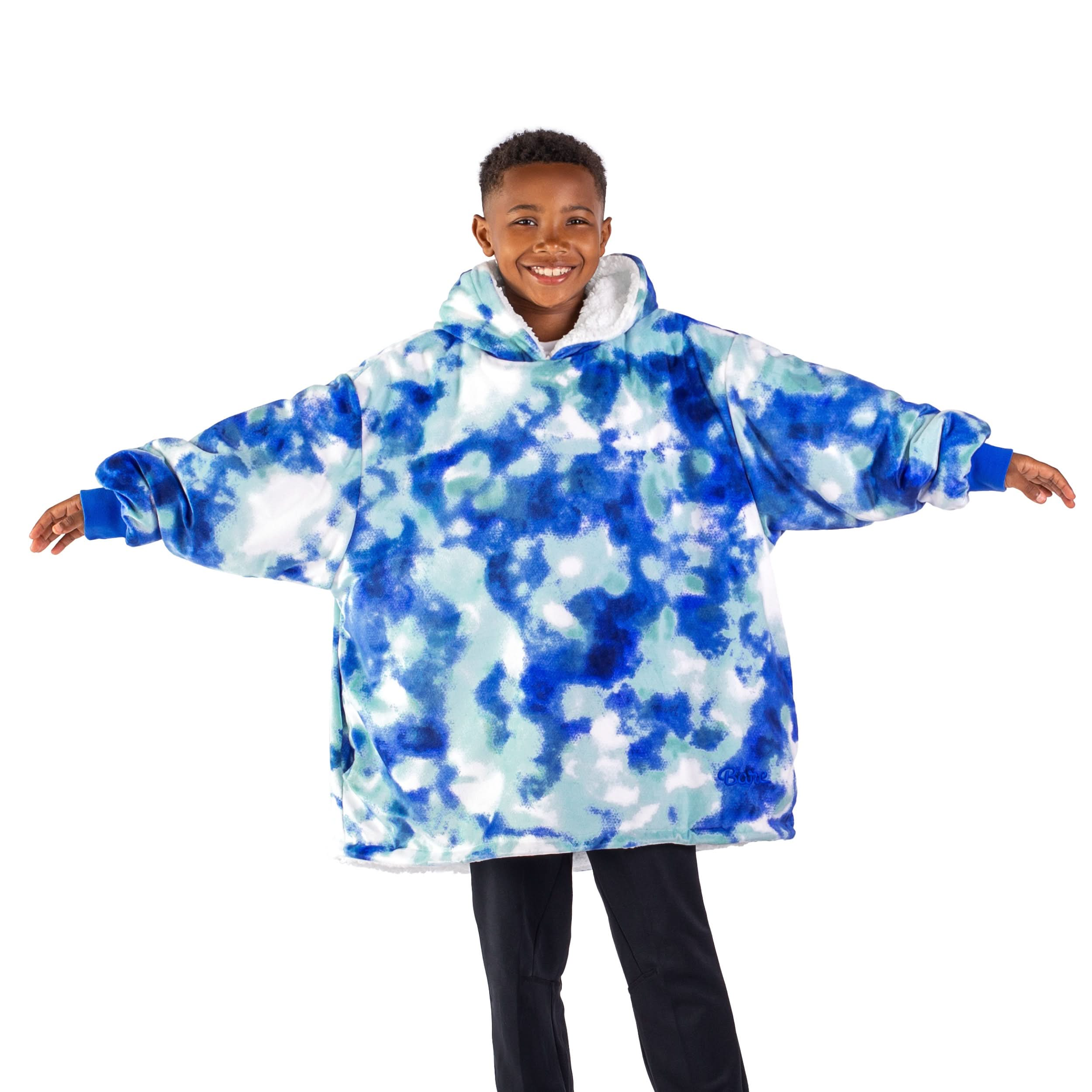 A boy standing with his arms stretched out while wearing a wearable blanket