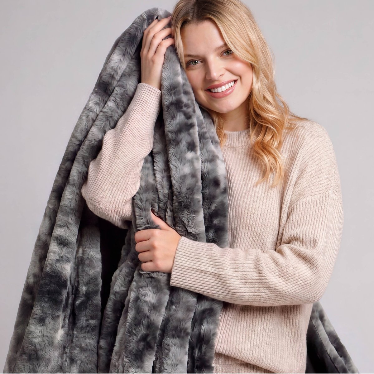 A smiling woman holding a faux fur blanket