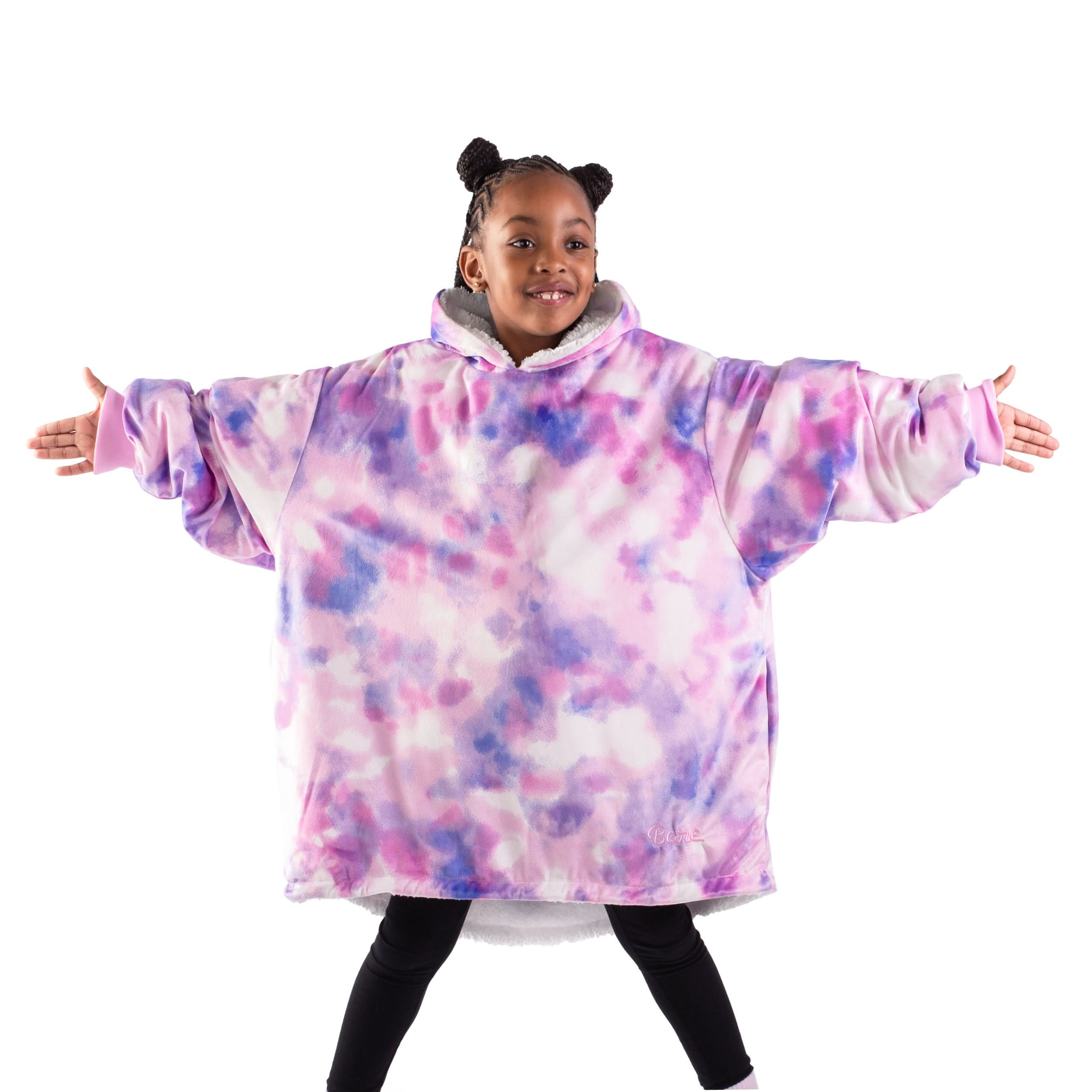 A girl standing with her arms stretched out while wearing a wearable blanket
