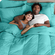 A couple is lying in bed with a comforter and sheets over them