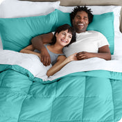 A couple is lying in bed with a comforter and sheets over them