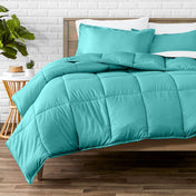 Comforter set on a bed with a white brick wall and plant in the background