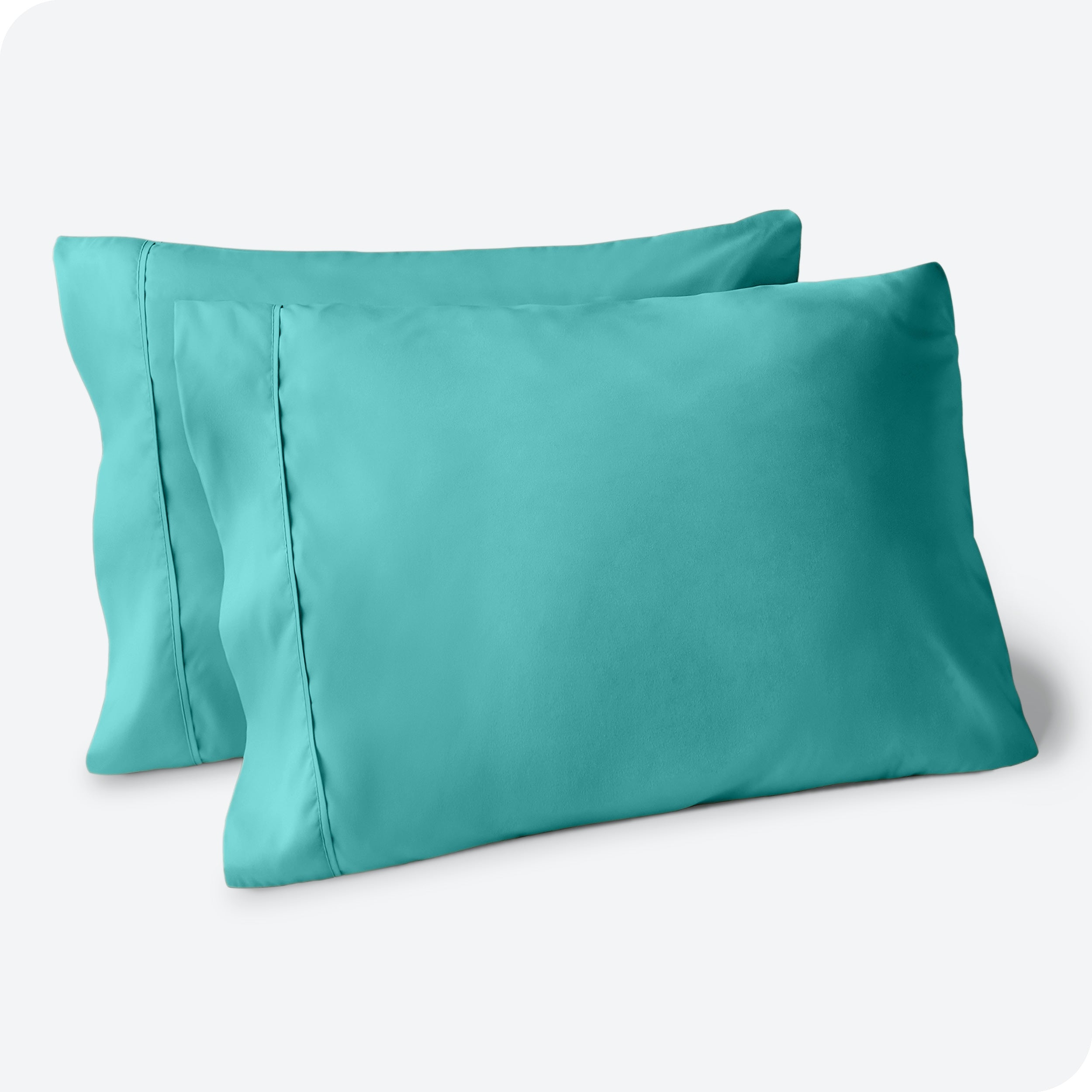 Two pillows on a white background with turquoise pillowcases on them