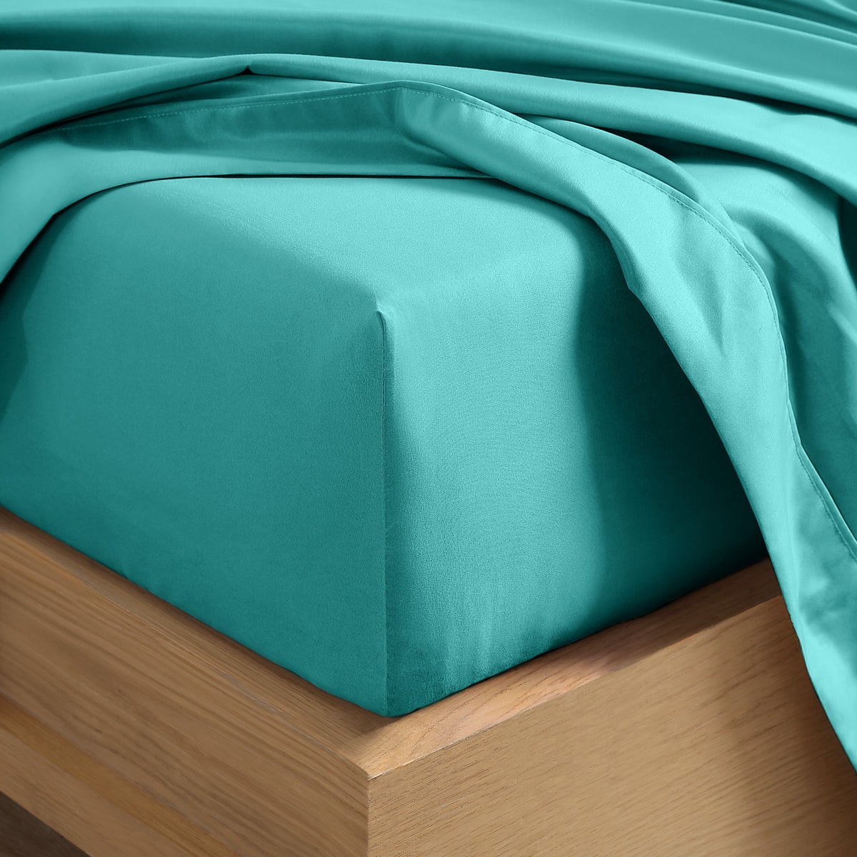 Close up of the corner of a mattress with a fitted sheet and flat sheet on it