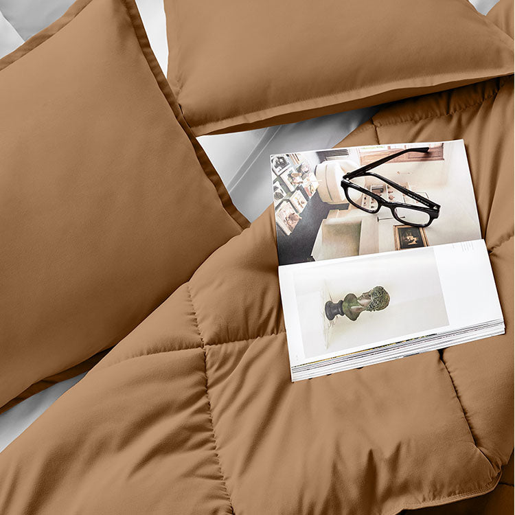 Brown Comforter with magazine and reading glasses on top of it