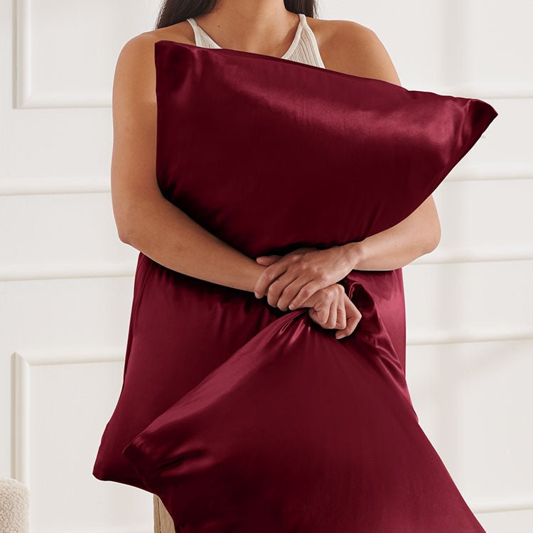woman squeezing a maroon mulberry silk pillow set