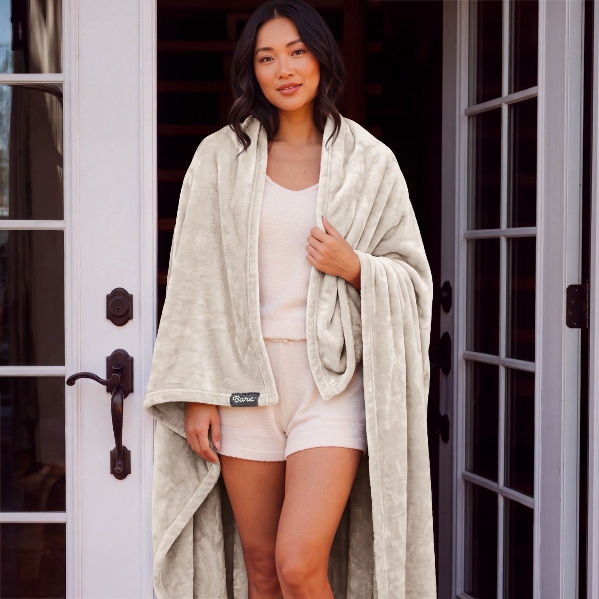 A woman standing with a microplush blanket wrapped around her