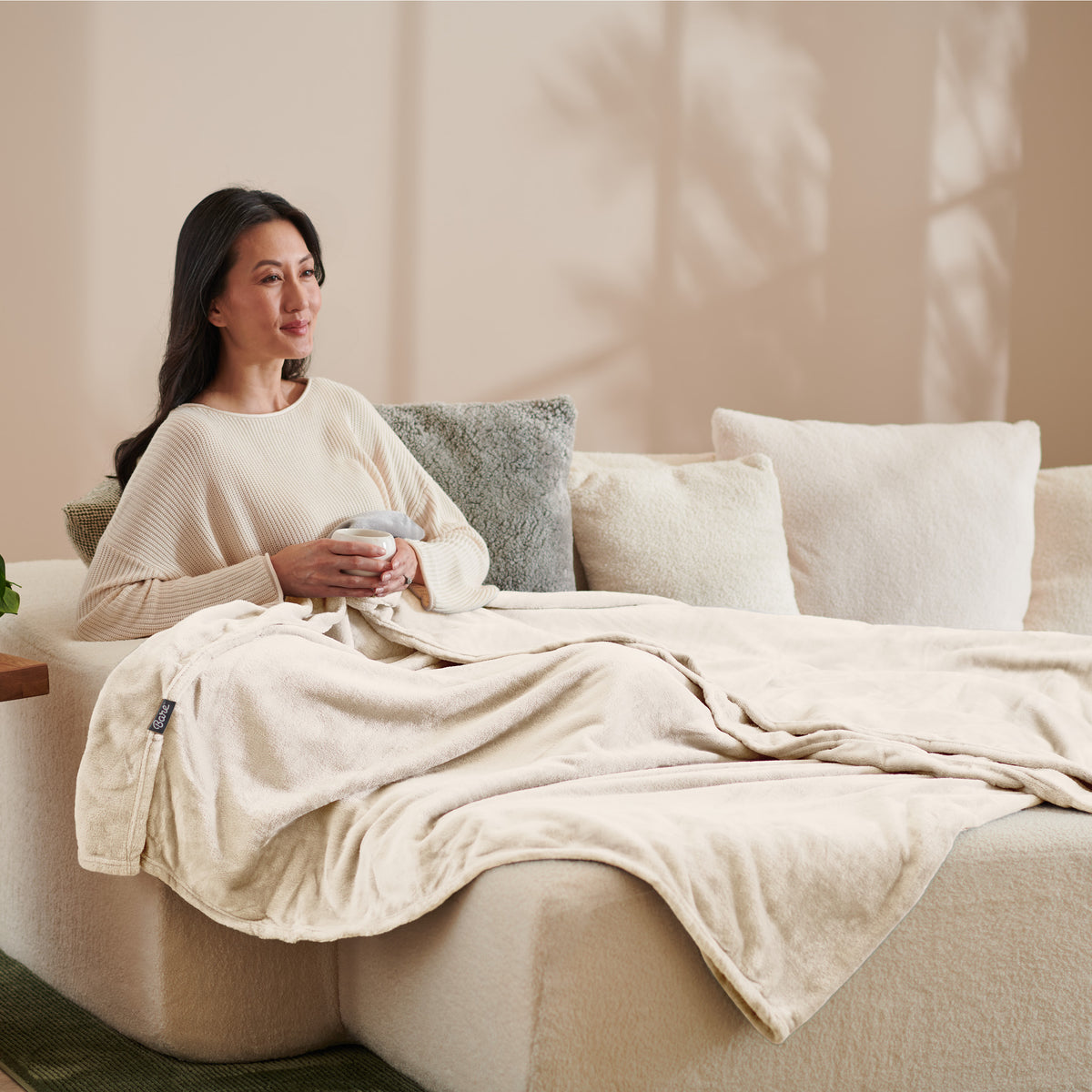 A woman sitting on a couch with a microplush blanket on her lap