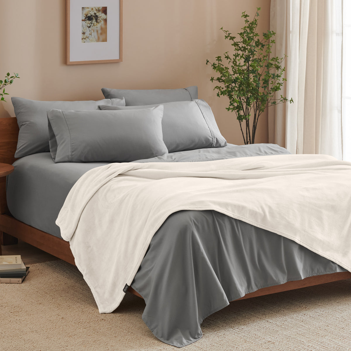 A bed made with grey sheets and a microplush blanket