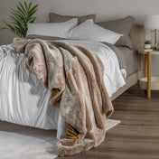 Blanket draped over a bed in a bedroom setting with a nightstand and lamp.
