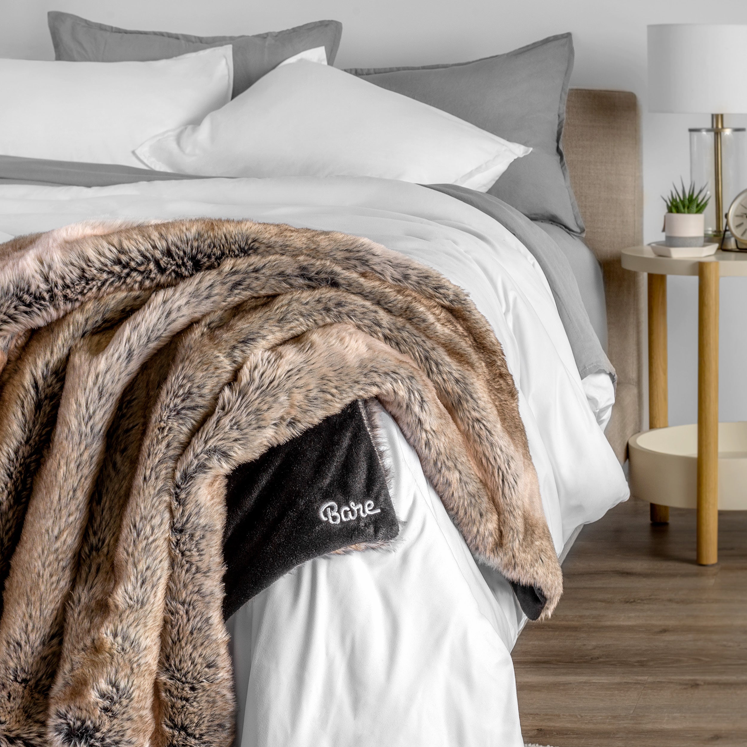 Blanket with 'Bare' branding on a bed in a bedroom setting