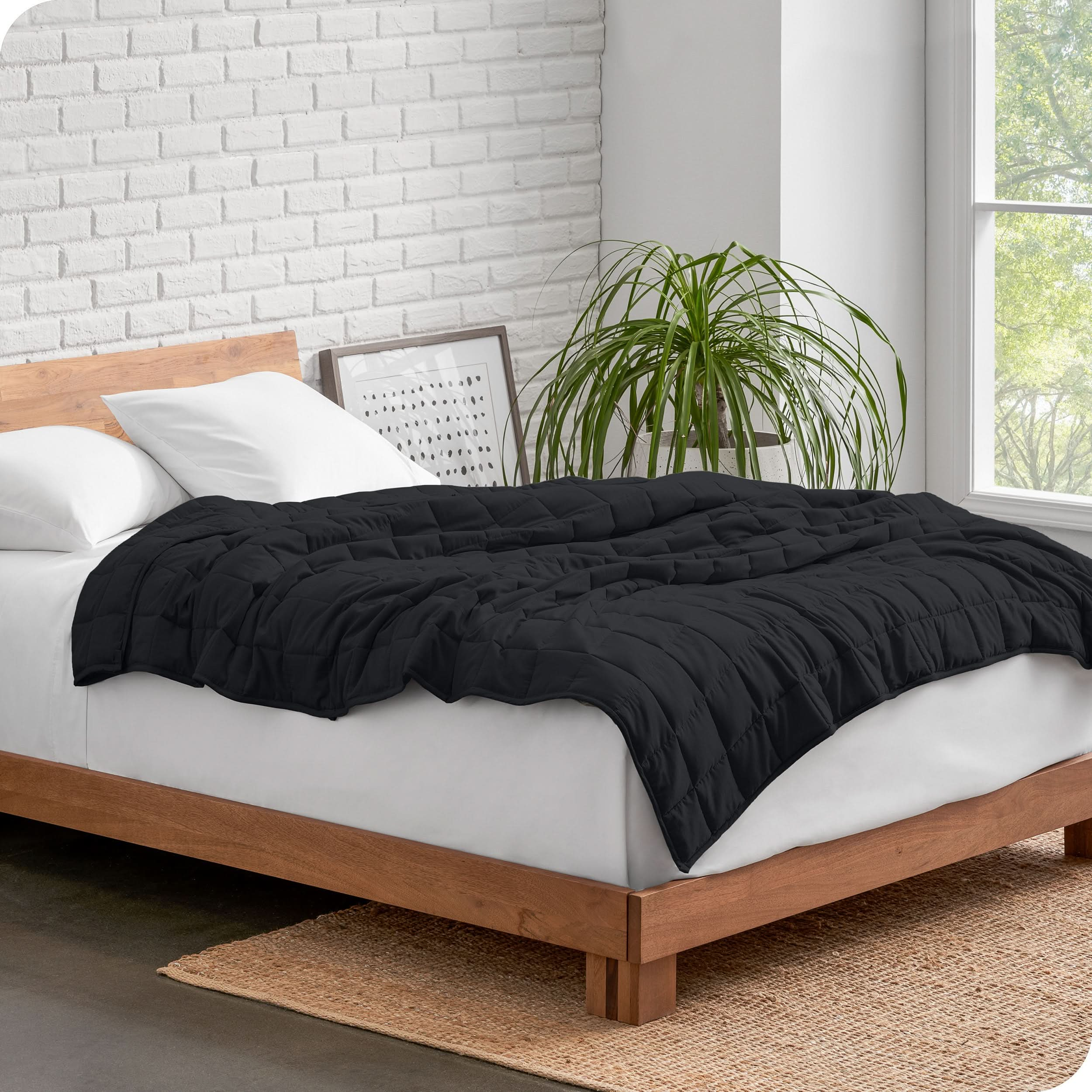 A side view of a modern bed in a white bedding with a weighted blanket on top of the bed.