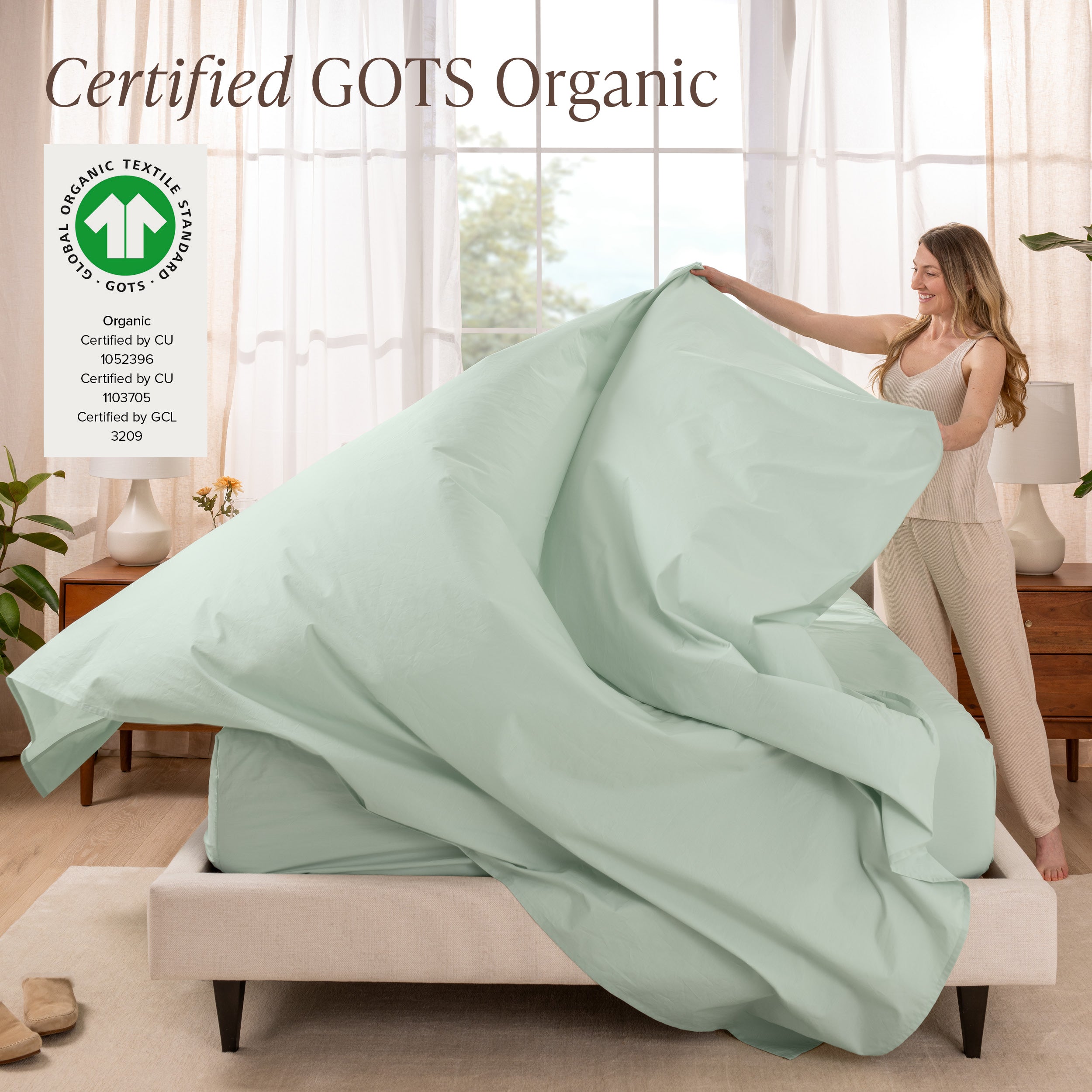 A woman is making a bed with organic cotton percale sheets