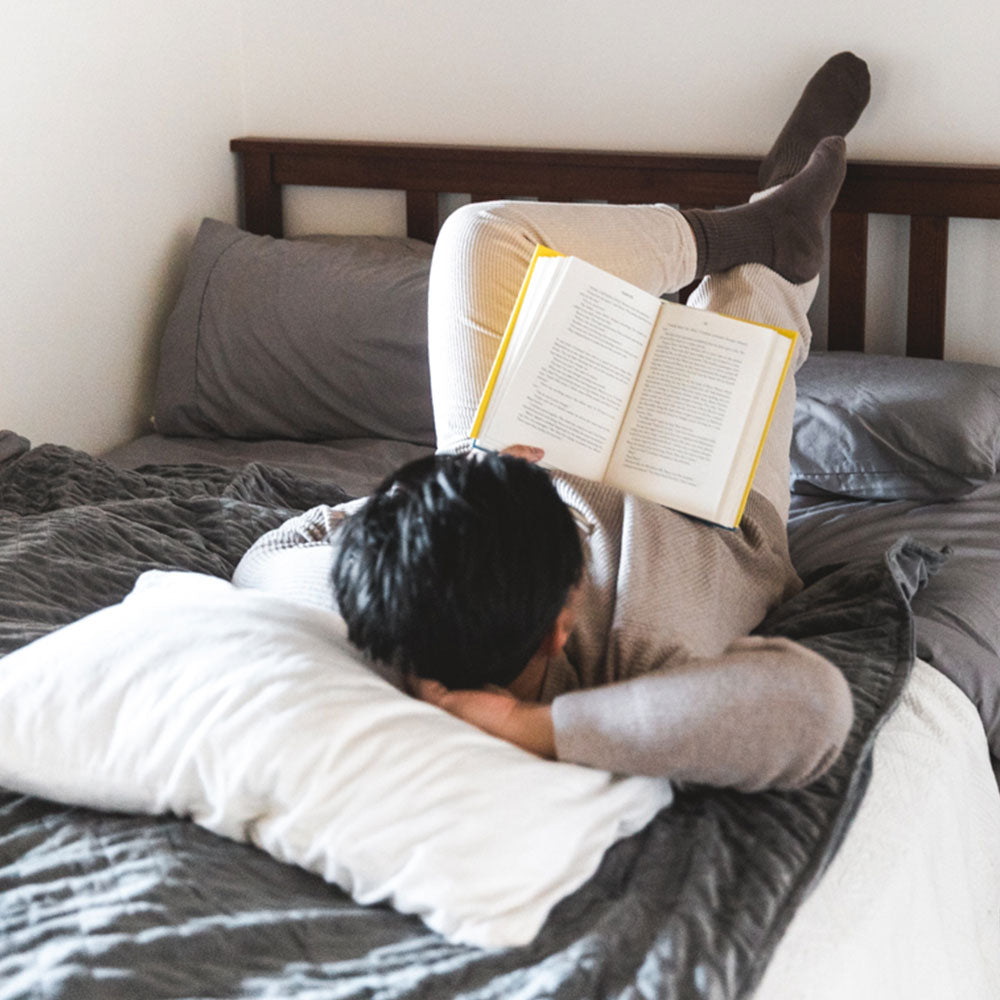 Guy reading a book with a weighted blanket over him
