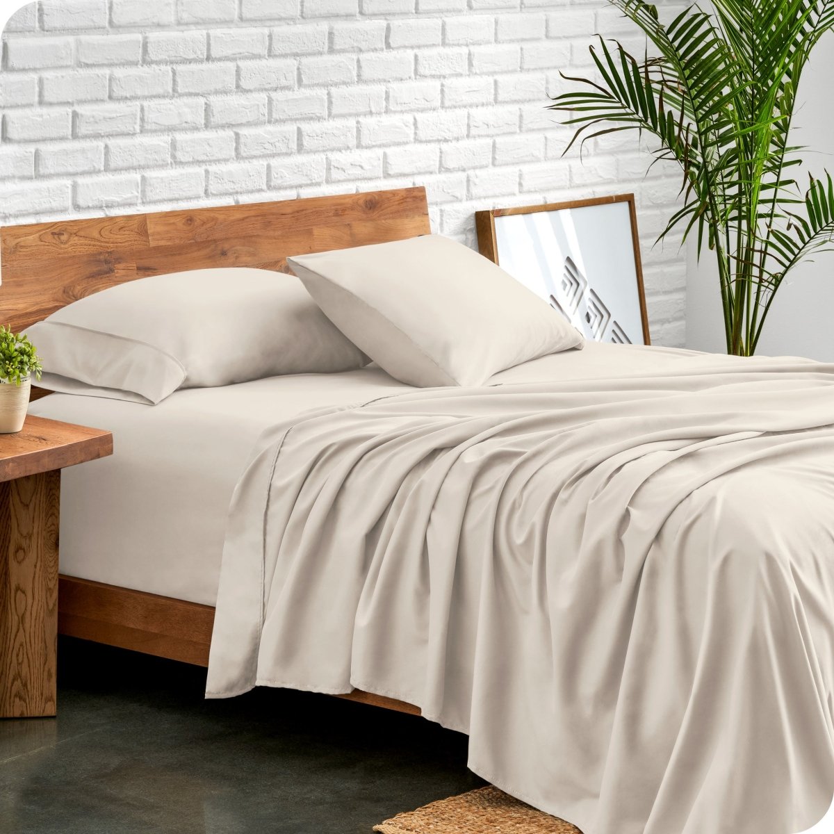 Bed with microfiber sheets against a white brick wall