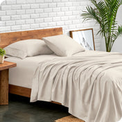 Bed with microfiber sheets against a white brick wall