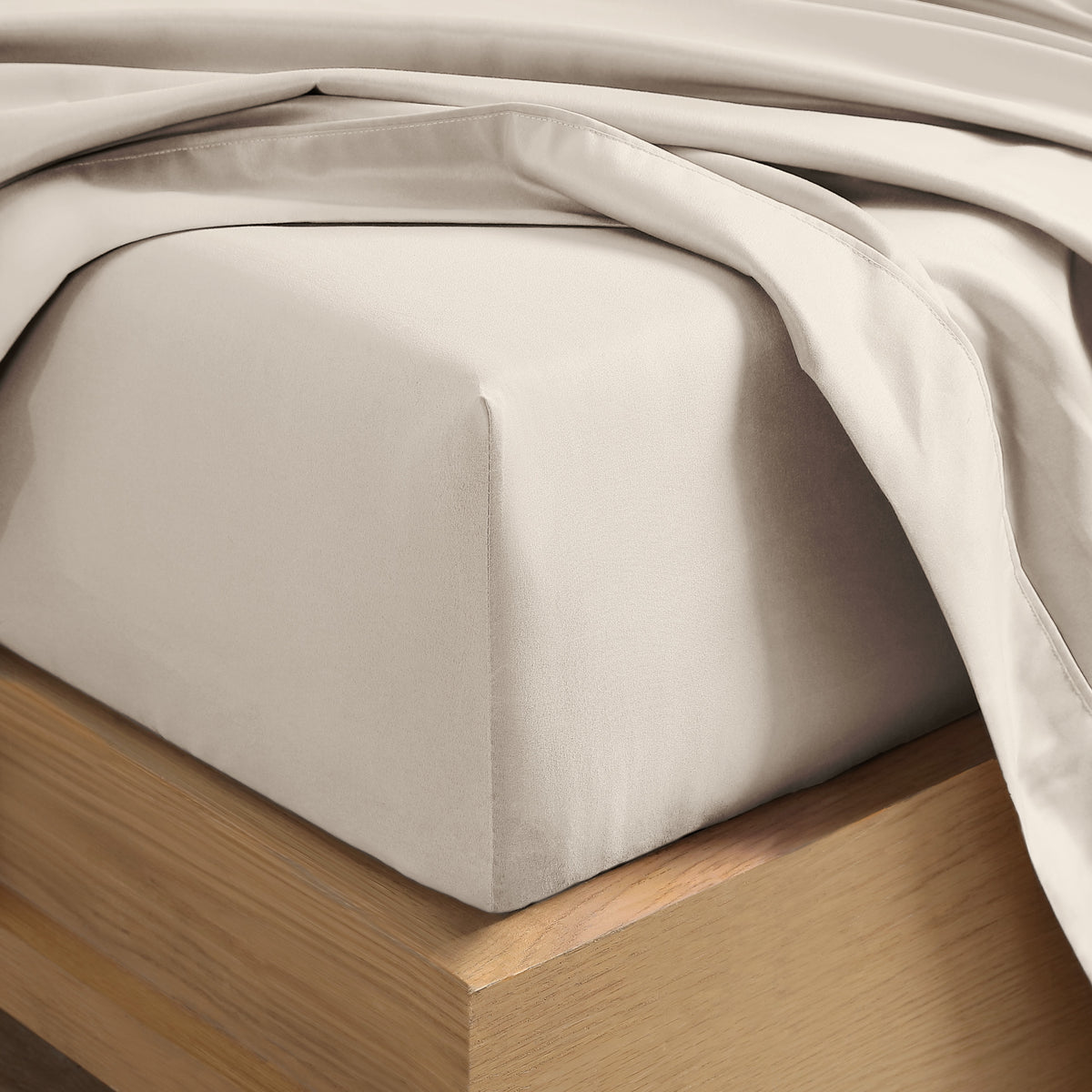 Close up of the corner of a mattress with a fitted sheet and flat sheet on it