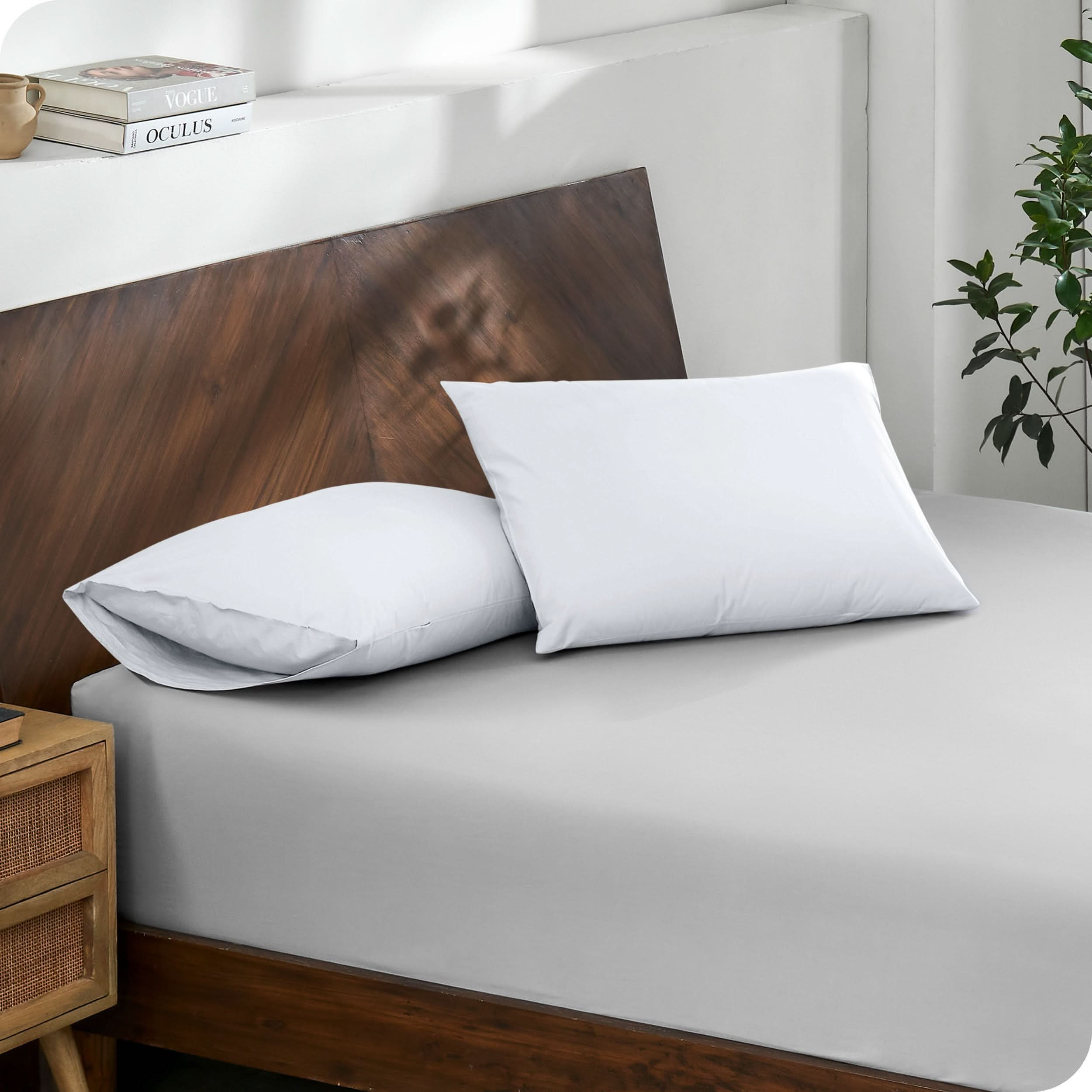 Diagonal view of modern wood bed with a fitted sheet and pillowcases

