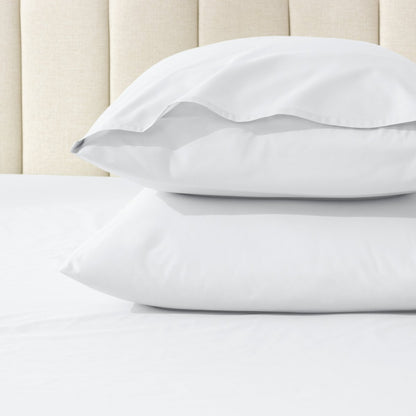 Two pillows stacked on a bed with percale pillowcases on them