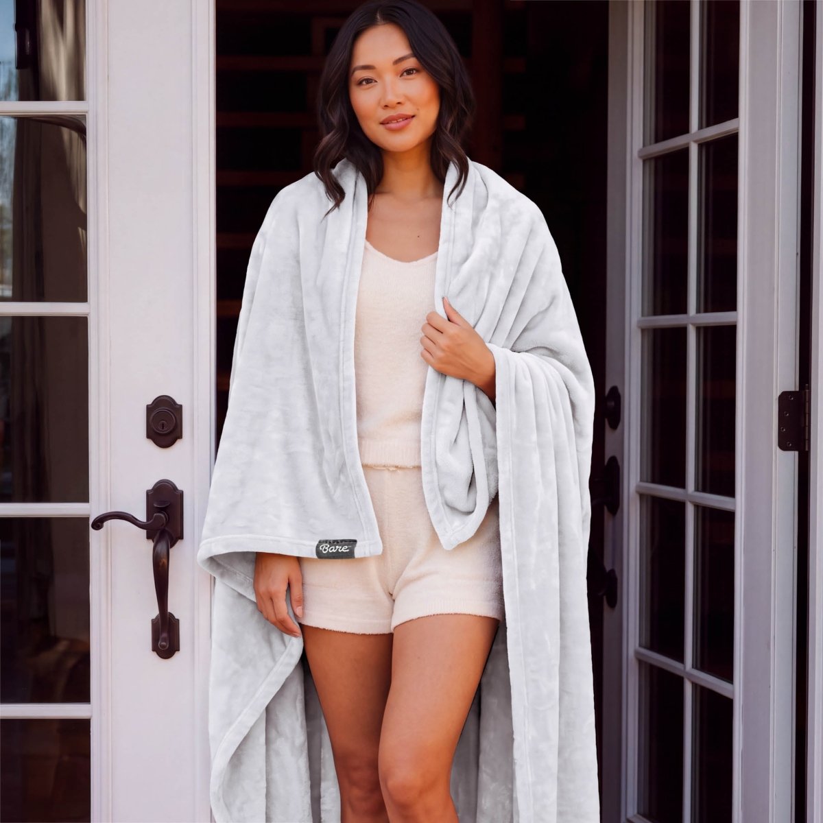 A woman standing with a microplush blanket wrapped around her