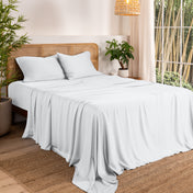Bamboo sheets on a bed in a bedroom with plants and a lamp.
