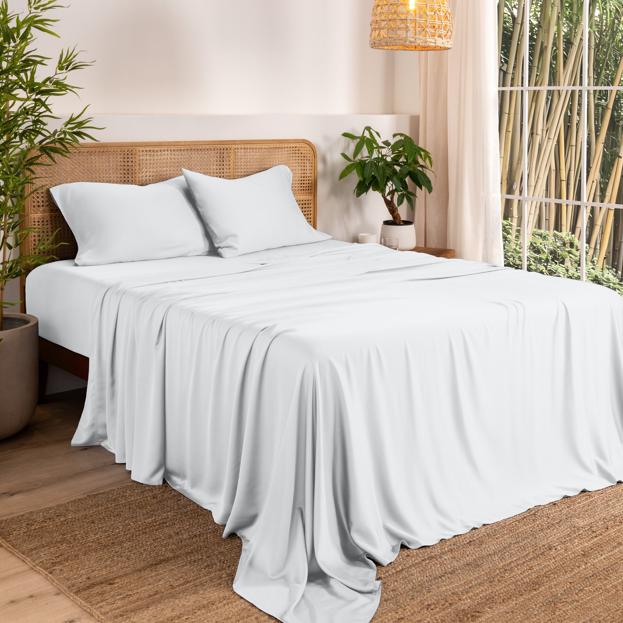 Bamboo sheets on a bed in a bedroom with plants and a lamp.