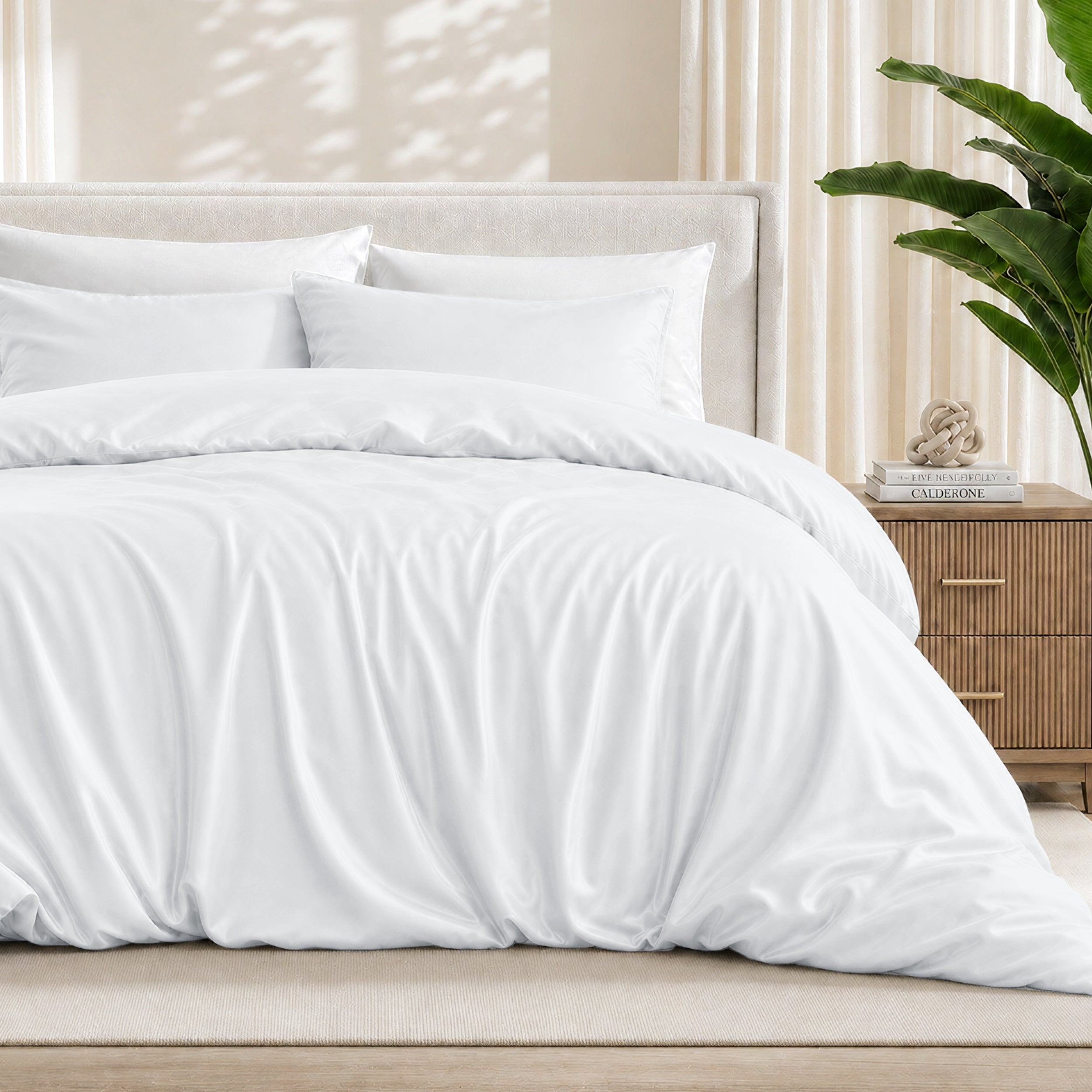 White duvet cover set on a bed in a bedroom setting with a plant and nightstand.