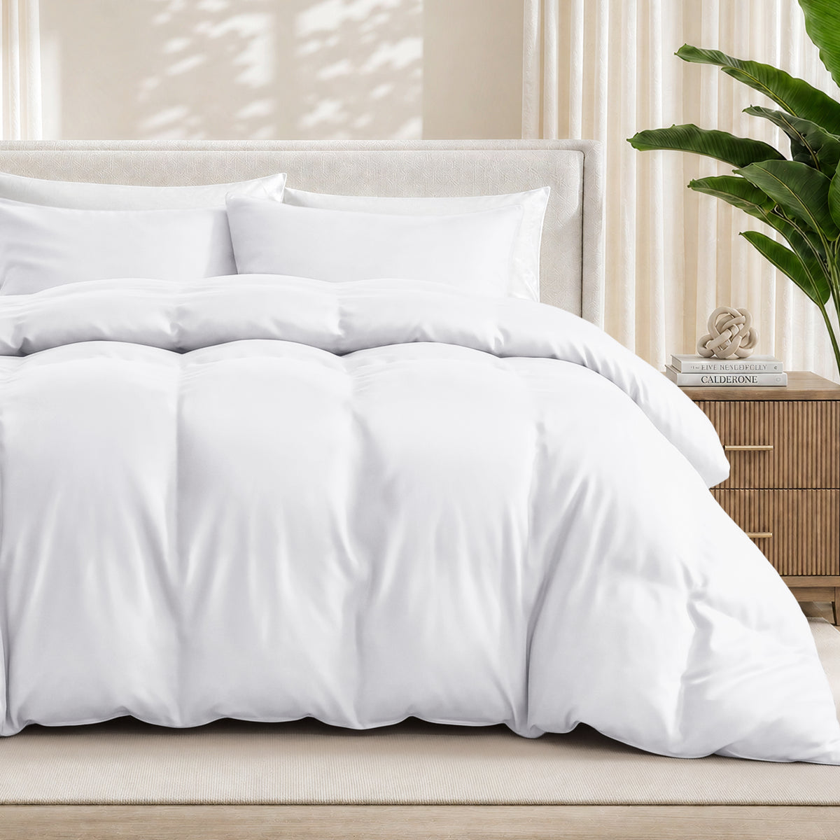 White duvet cover set on a bed in a bedroom setting with a plant and nightstand.