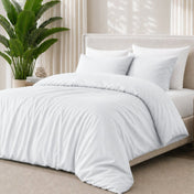 White bedding set on a bed with a plant in the background
