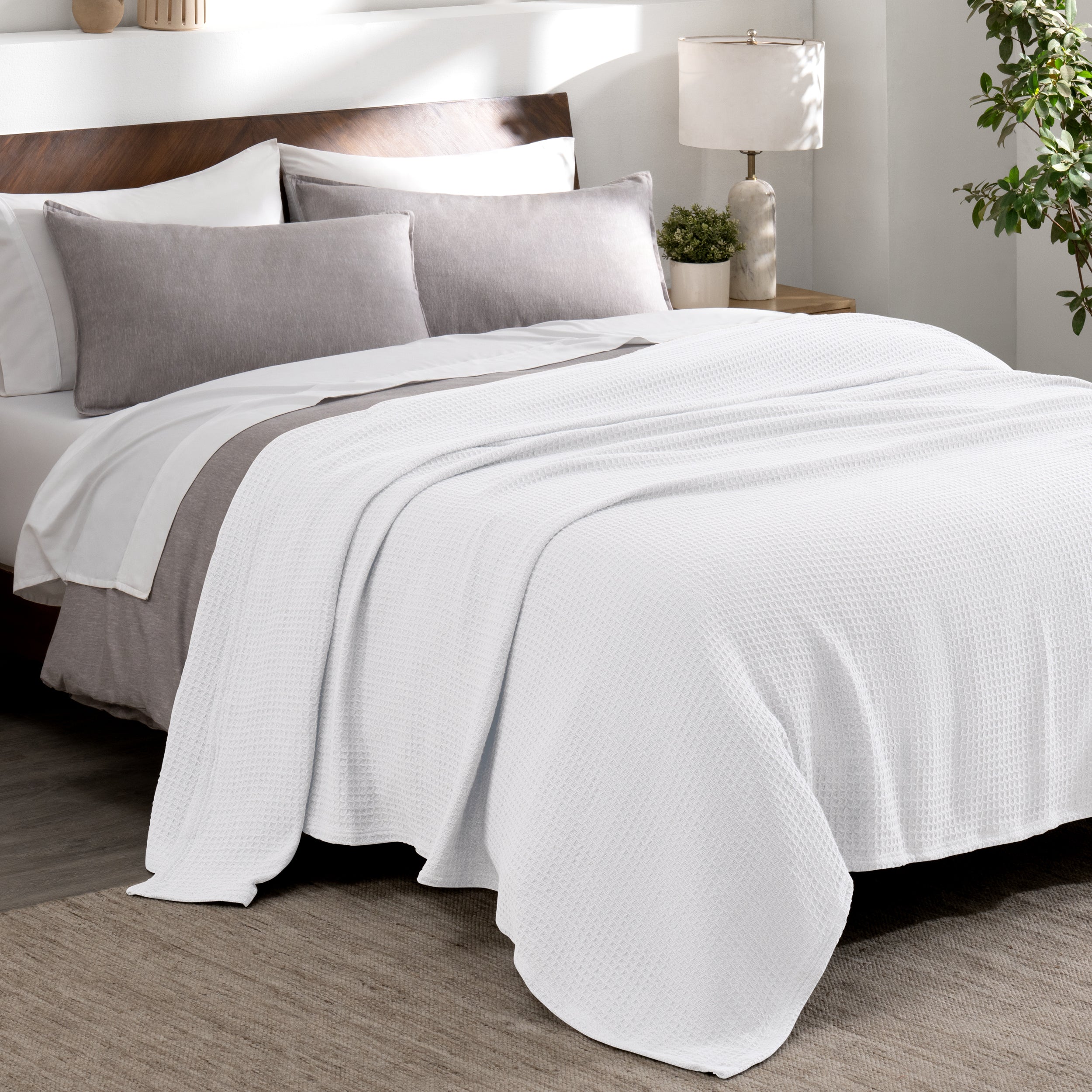 Cotton waffle blanket draped over a bed with pillows in a bedroom setting.